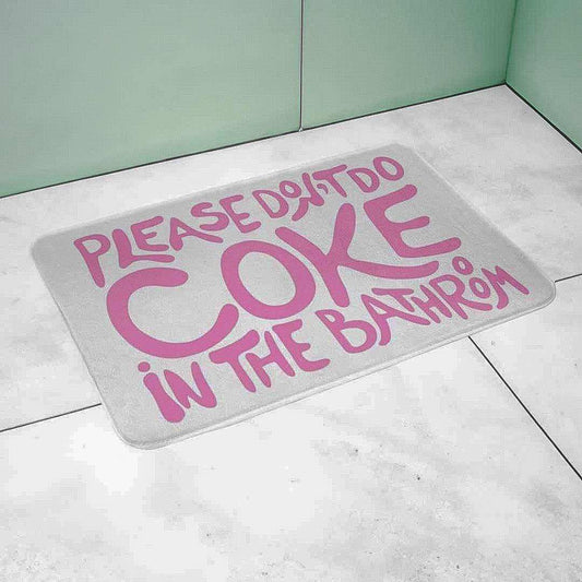 Gray bath mat with pink text on a tiled bathroom floor