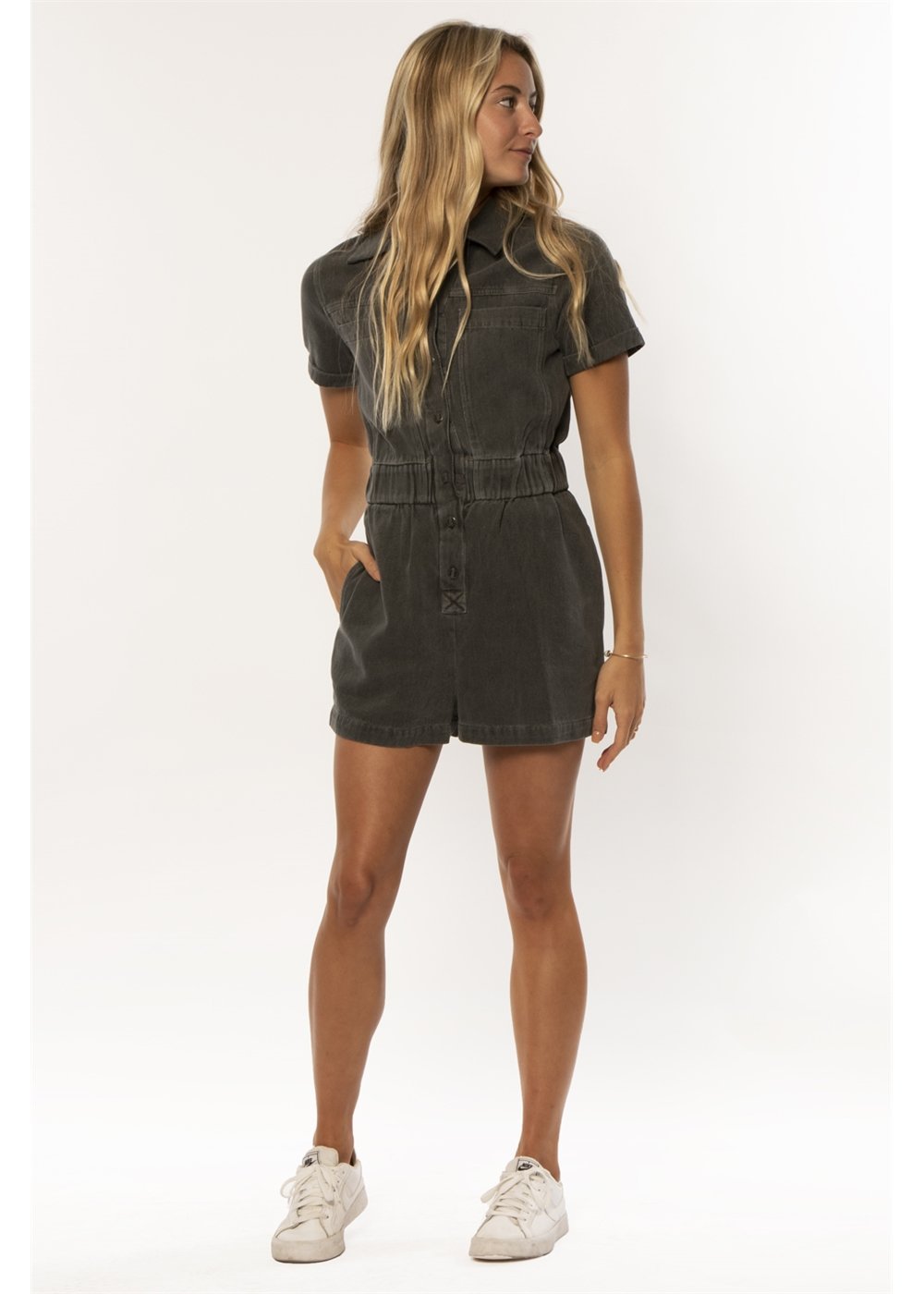 Woman wearing a dark denim romper on a white background