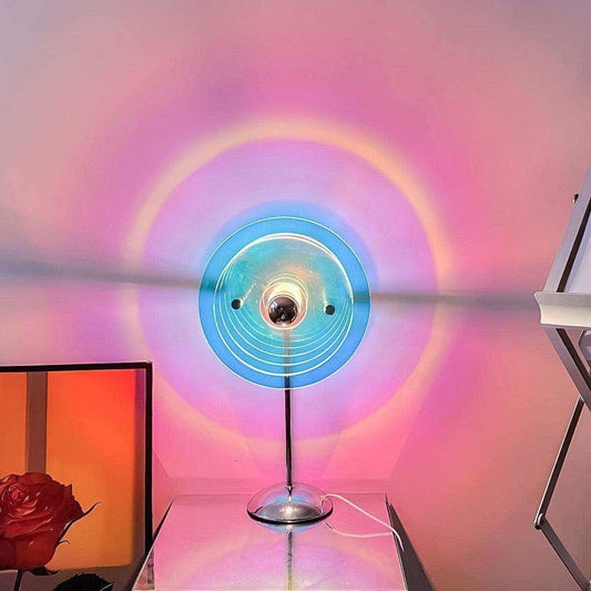 Colorful circular light fixture casting a rainbow pattern on a wall with a red rose in the foreground.