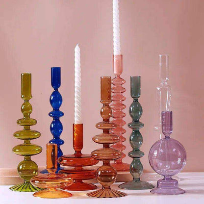 Colorful glass candle holders on a pink background