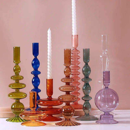 Colorful glass candle holders on a pink background