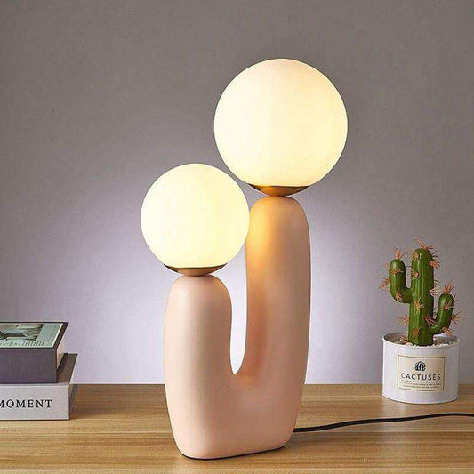 Modern table lamp with two spherical lights on a wooden surface.