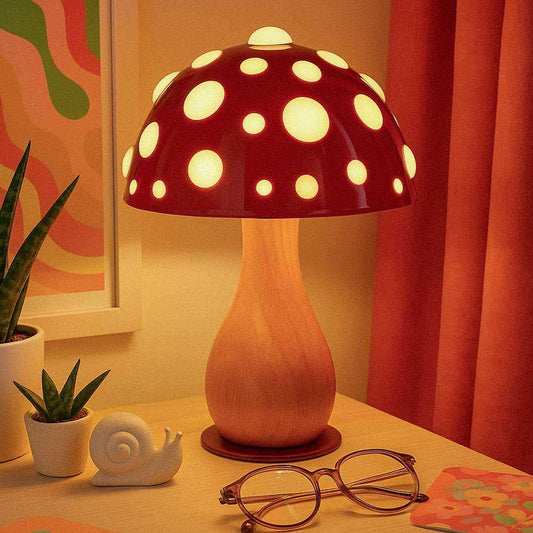 Mushroom-shaped lamp with polka dot design on a table with plants and glasses.