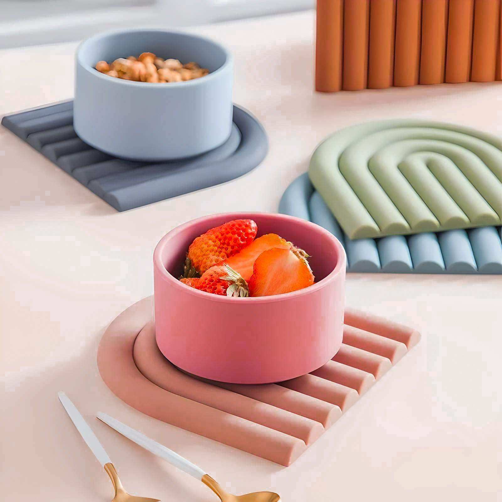 Colorful bowls with food on a table with various coasters and a candle.