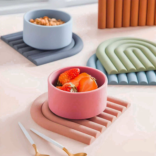 Colorful bowls with food on a table with various coasters and a candle.
