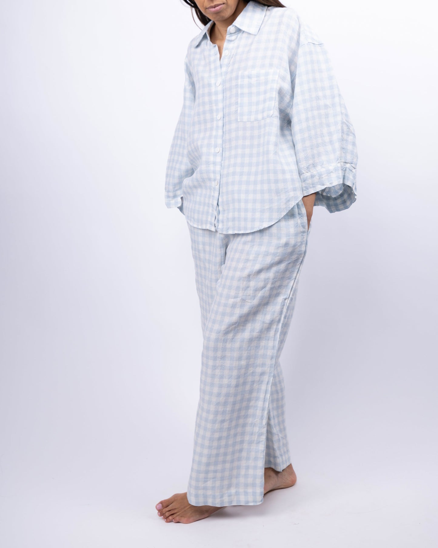 Person wearing a light blue checkered pajama set on a white background