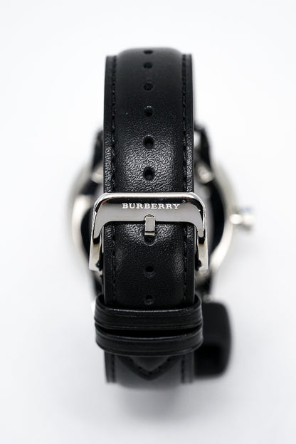Black Burberry watch with leather strap on a white background